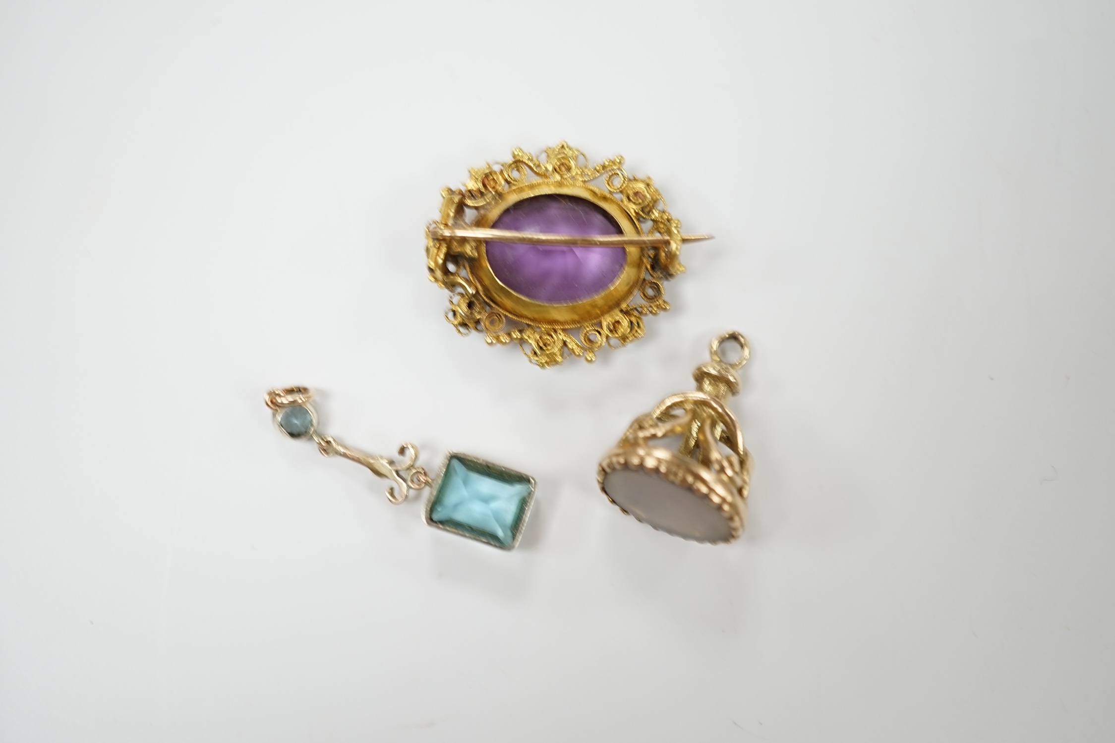 An early 20th century yellow metal, amethyst and turquoise set brooch, 25mm, a 9ct gold and white chalcedony set fob and a yellow metal and gem set drop pendant. Condition - poor to fair